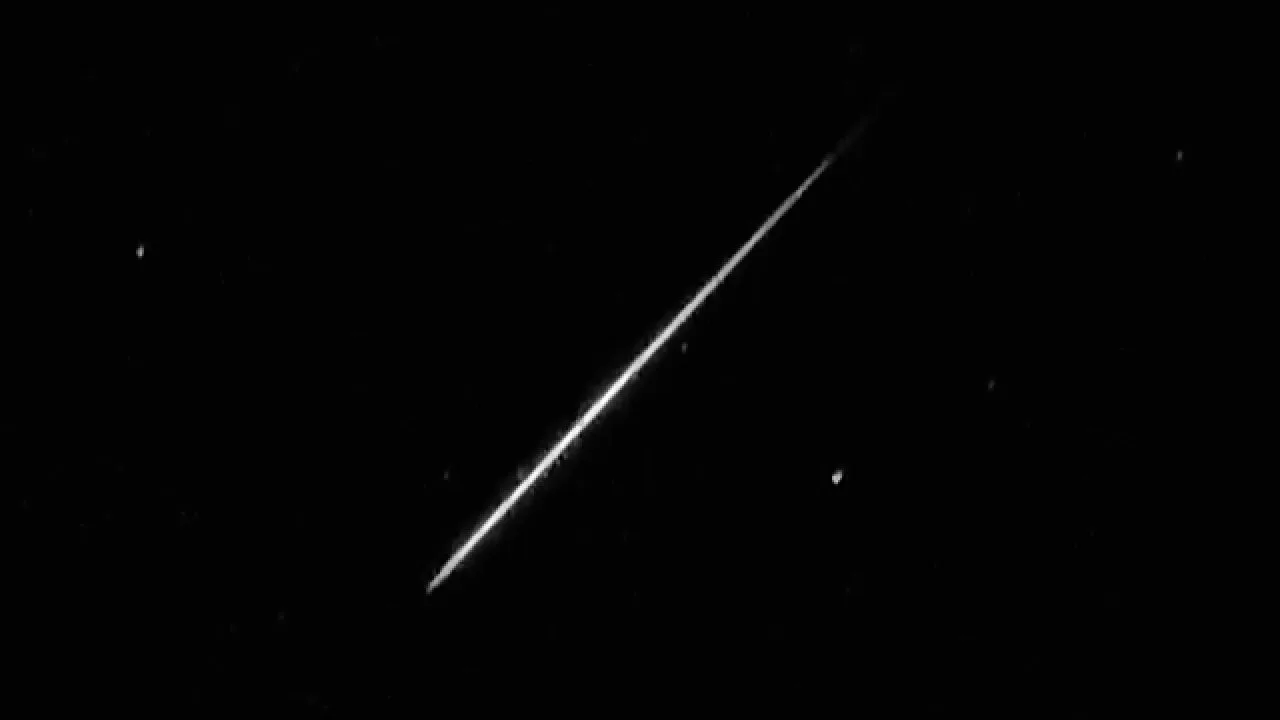 A bright meteor streak crossing a dark star field diagonally.